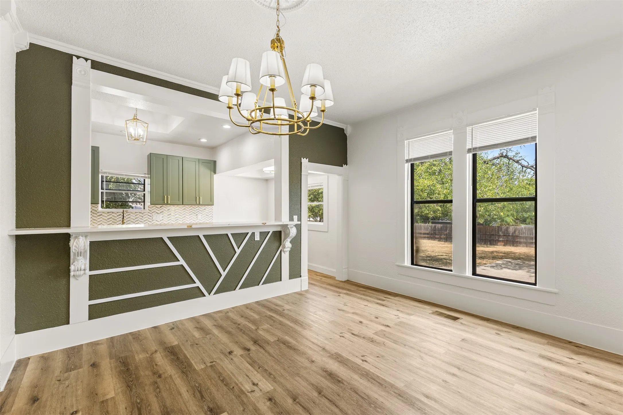 Wood-finish flooring, decorative wall paneling, and an elegant chandelier