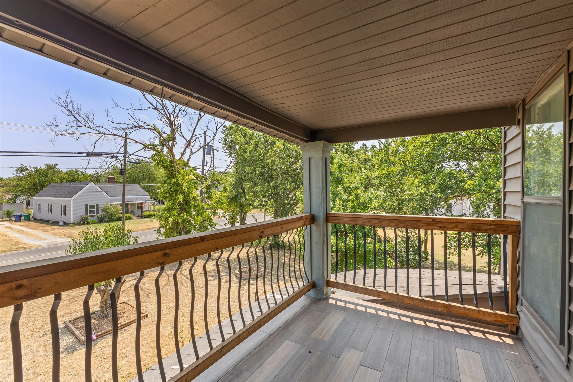 Covered balcony featuring wood-finish flooring, wood railing, and decorative balusters