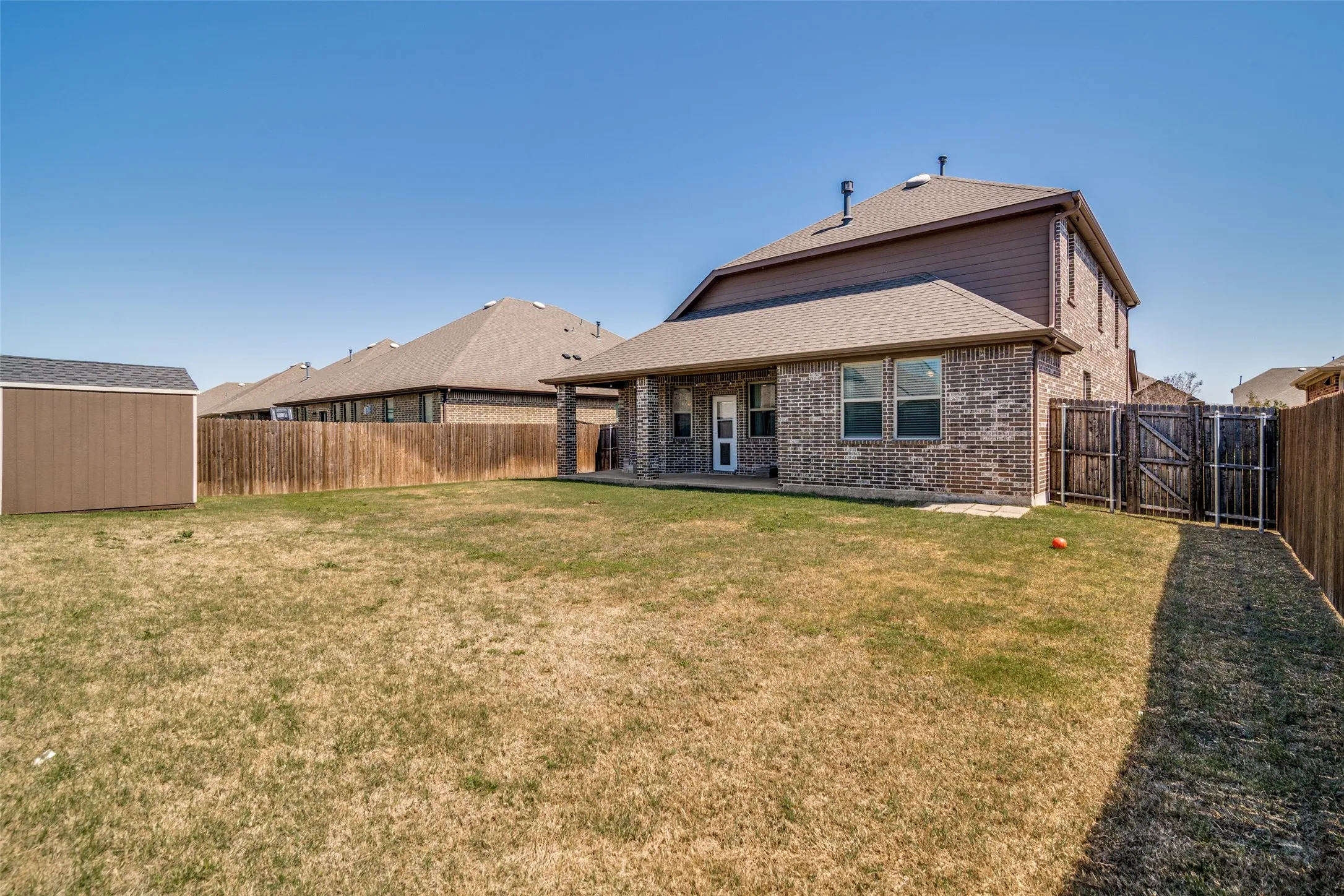 Large back yard with a covered patio and storage shed