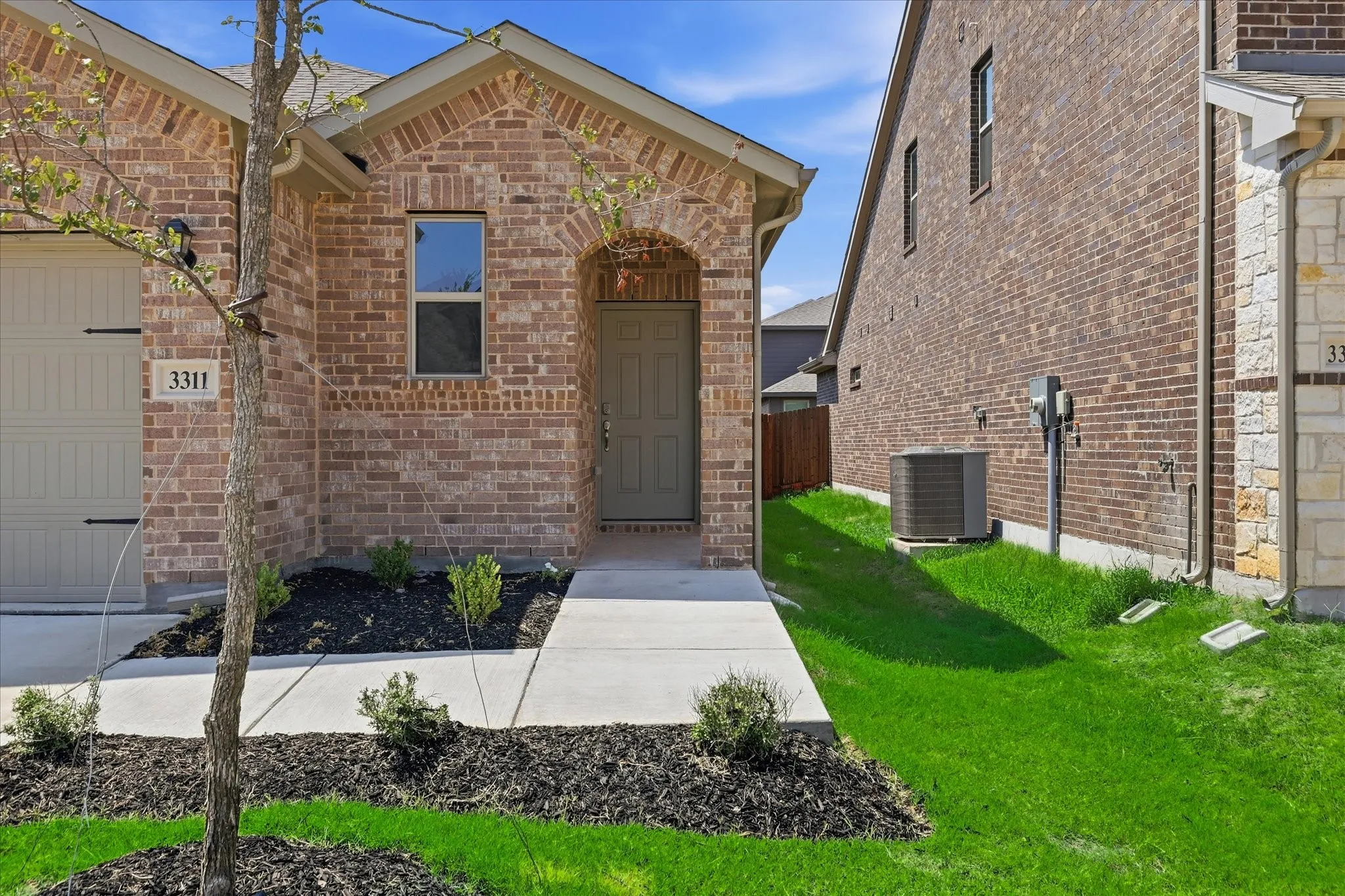 Brick facade entry featuring an arched doorway and a covered porch