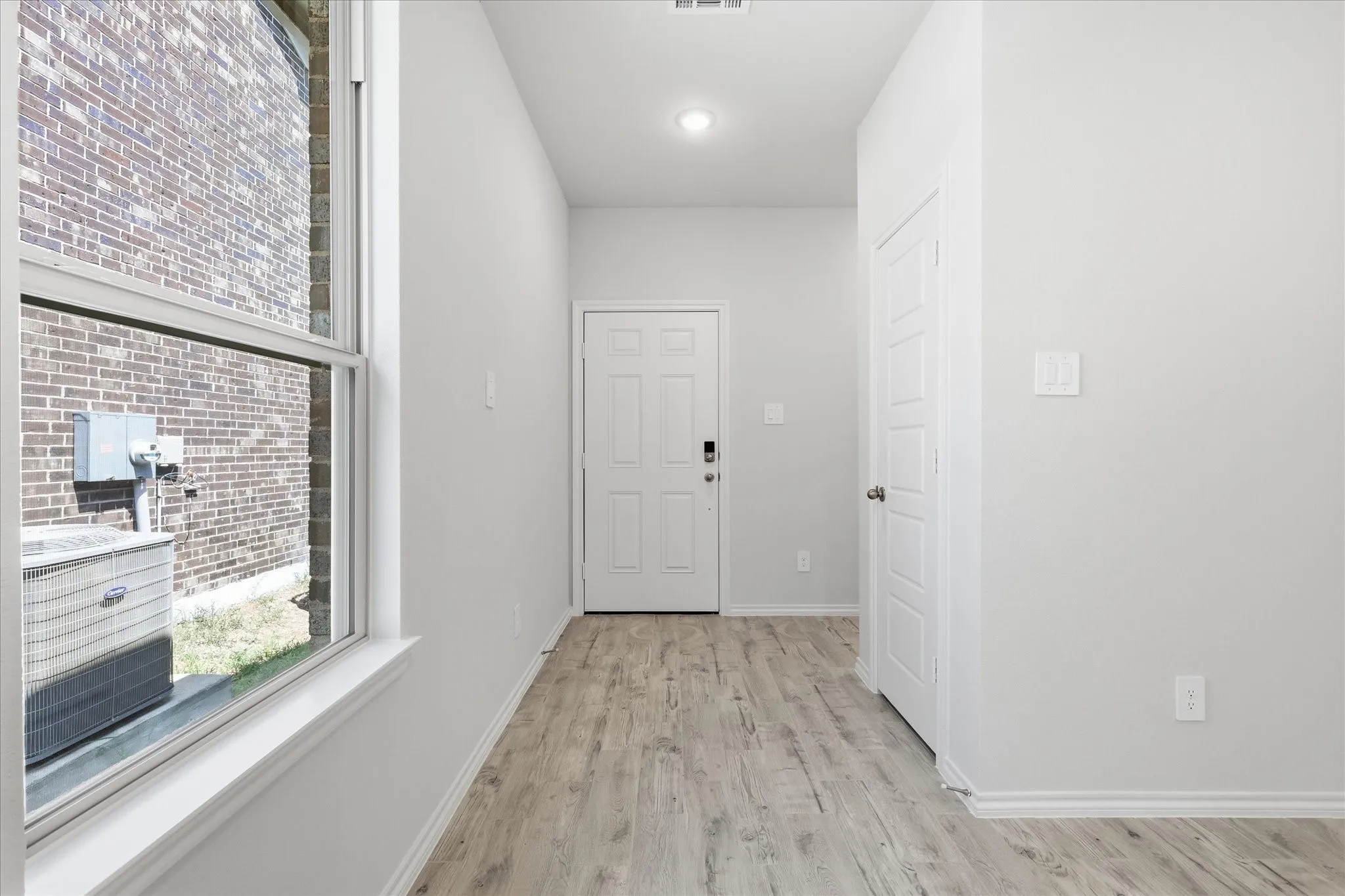 Entrance into the home with corridor. Door on the right is the coat closet. The corridor on the right takes you to Laundry Room and Garage.
