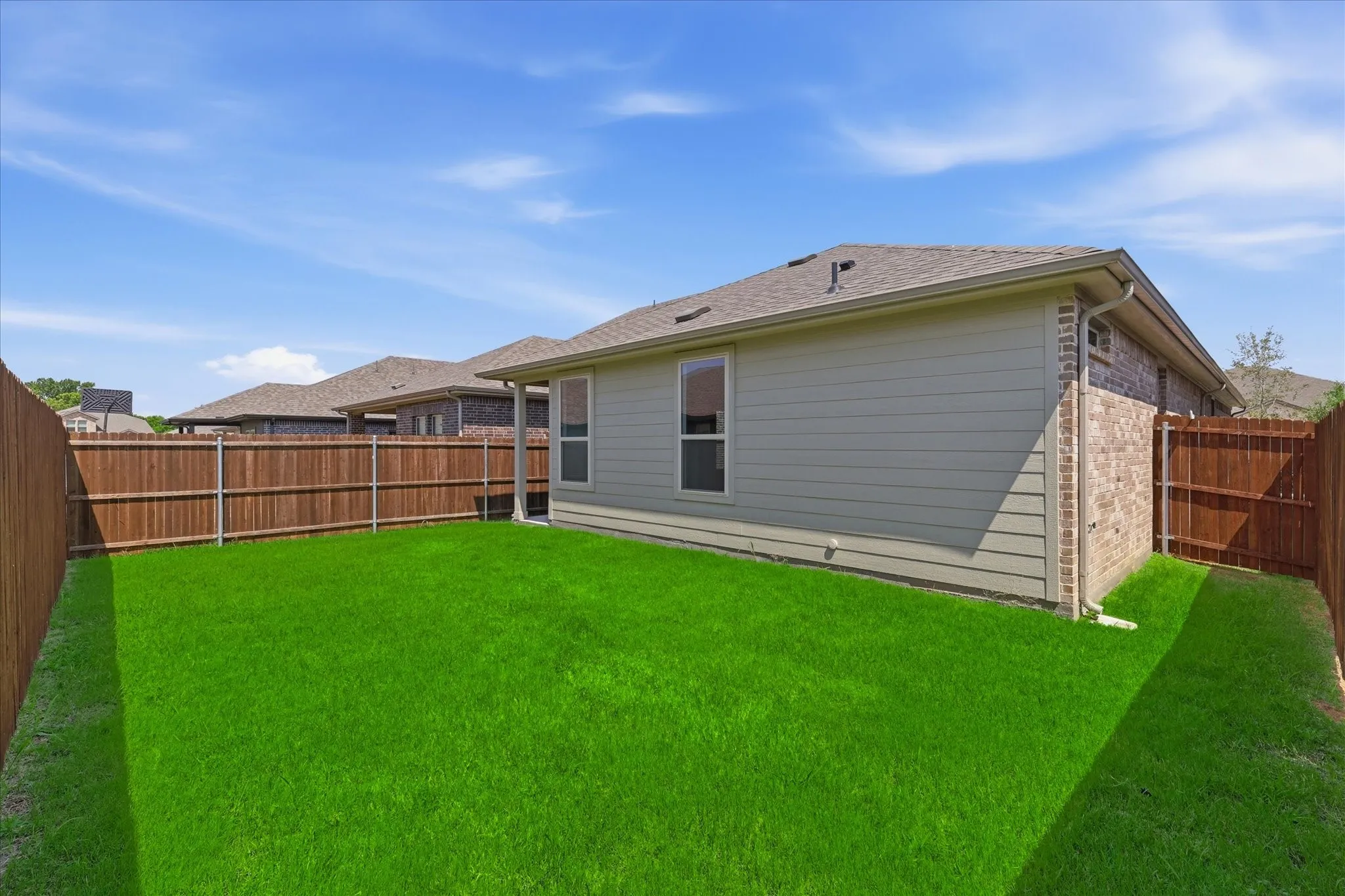 Backyard featuring a lawn, full privacy fencing, and a combination of brick and siding exterior finishes