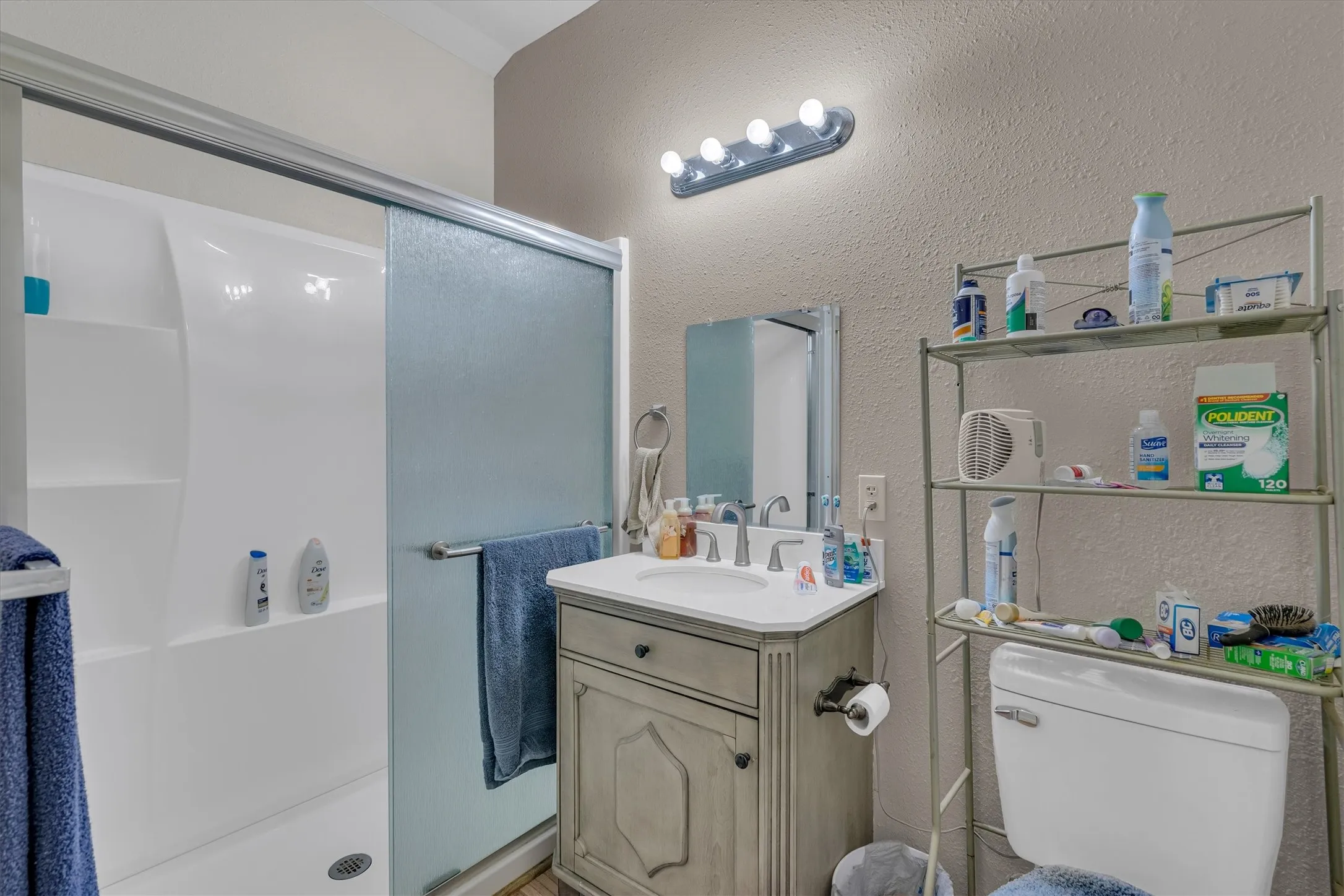Bathroom featuring a vanity with an integrated sink, a rectangular mirror, and a shower with sliding glass doors