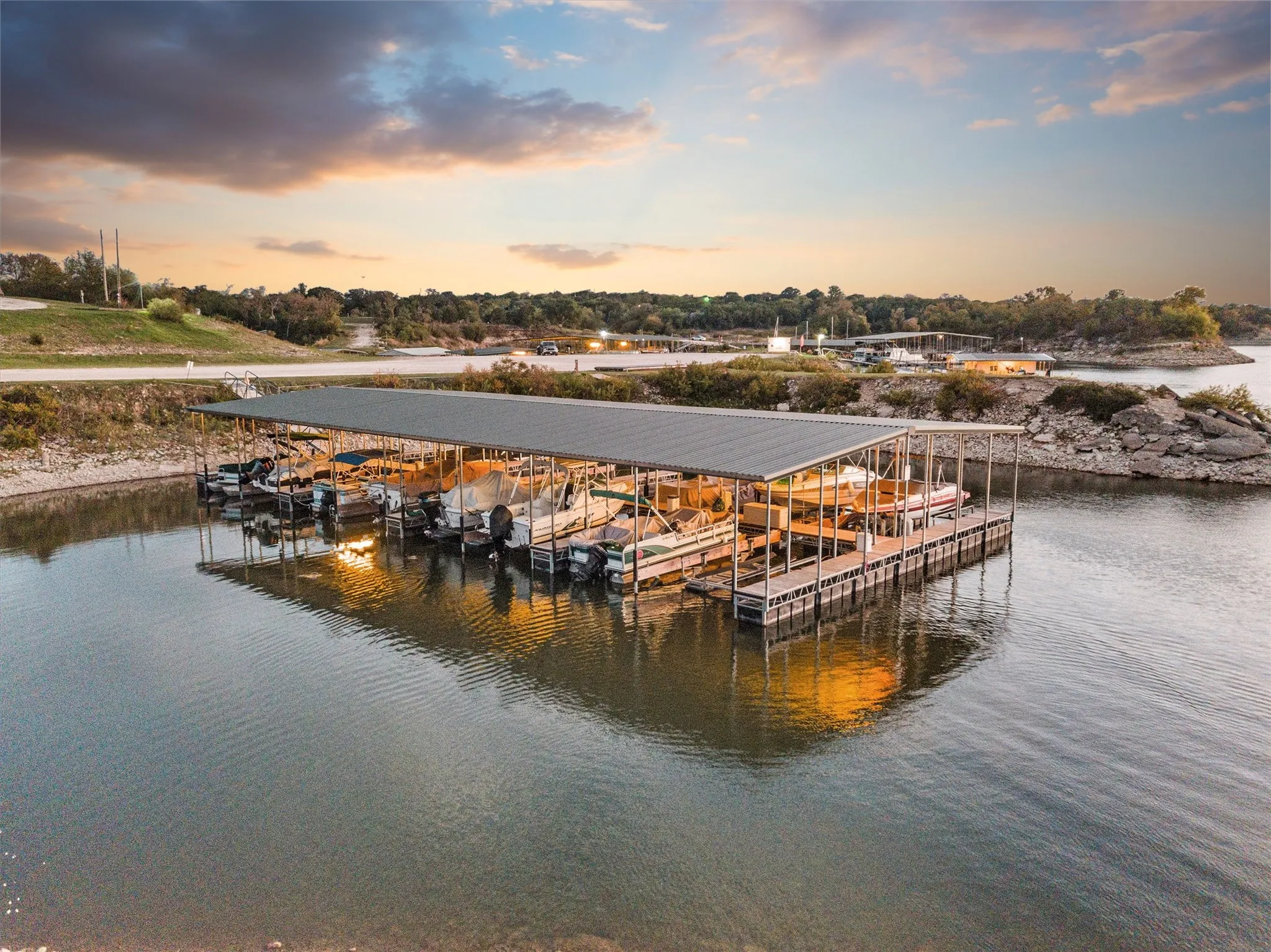 Floating boat dock with multiple covered slips, metal roof, and surrounding tranquil waters