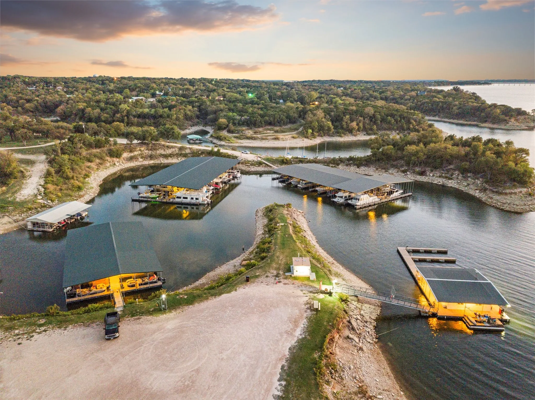 Expansive marina property featuring multiple covered boat slips, direct water access, a substantial dock system, and surrounding wooded shoreline