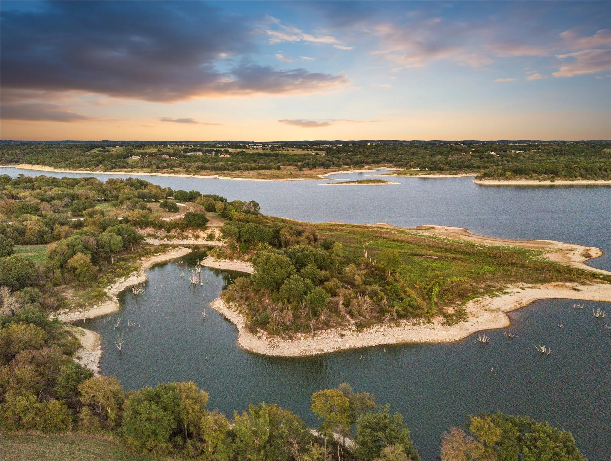 Aerial perspective showcasing a large body of water bordered by natural shorelines and dense deciduous trees