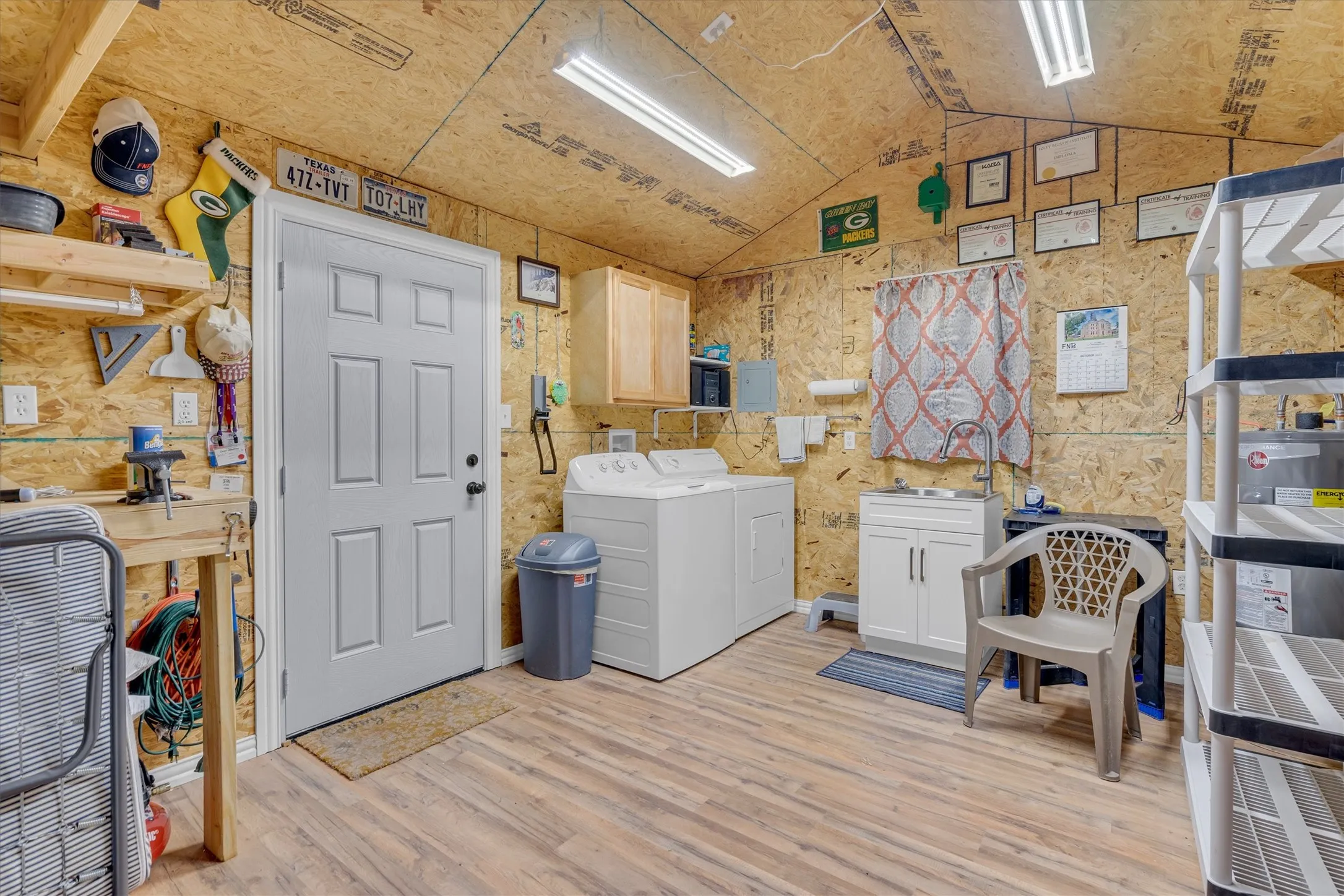 Utility room featuring wood-finish flooring, a white paneled door, and built-in shelving