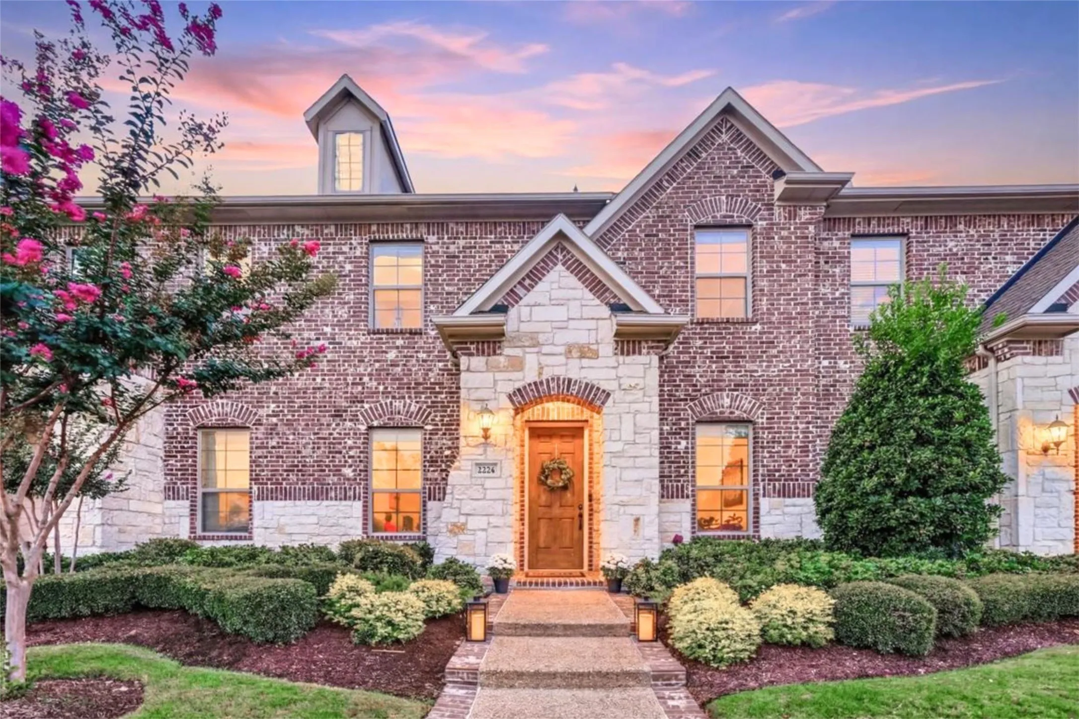 Brick and stone facade featuring an arched entryway with a wooden front door