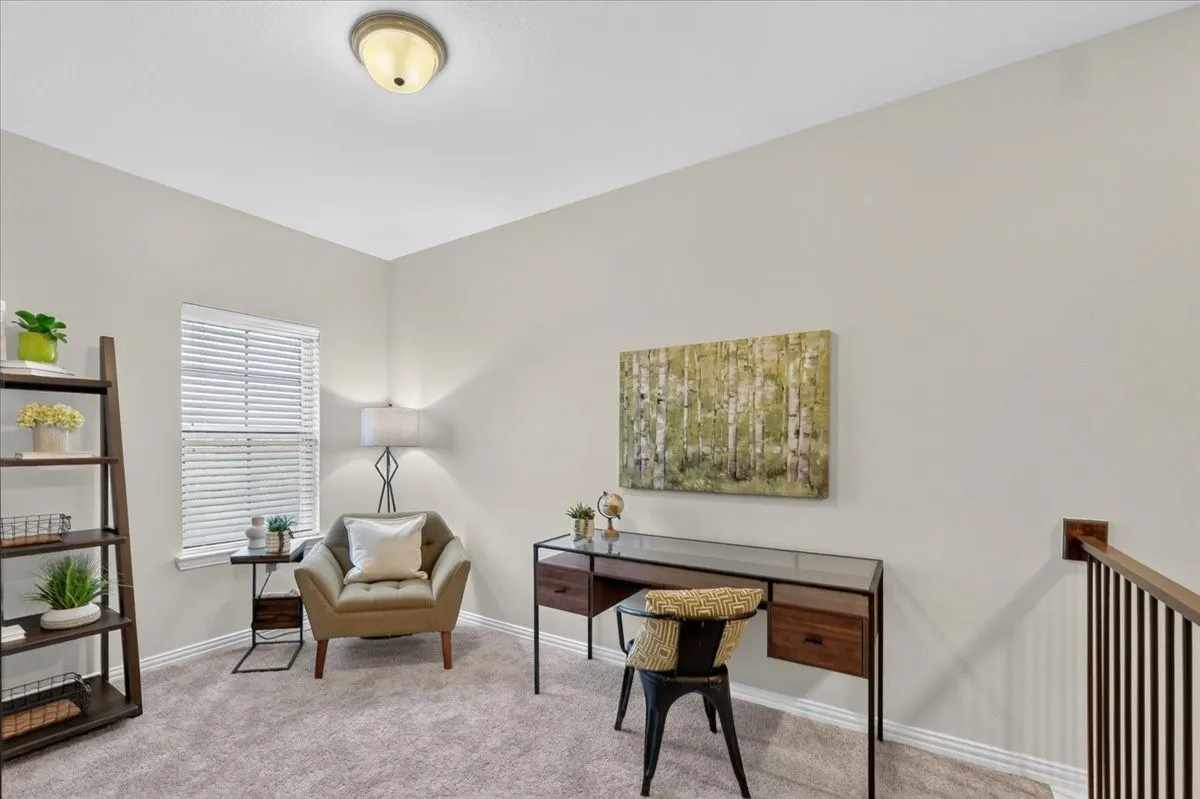 Carpeted interior space featuring light-toned walls, white trim, and a prominent window with blinds