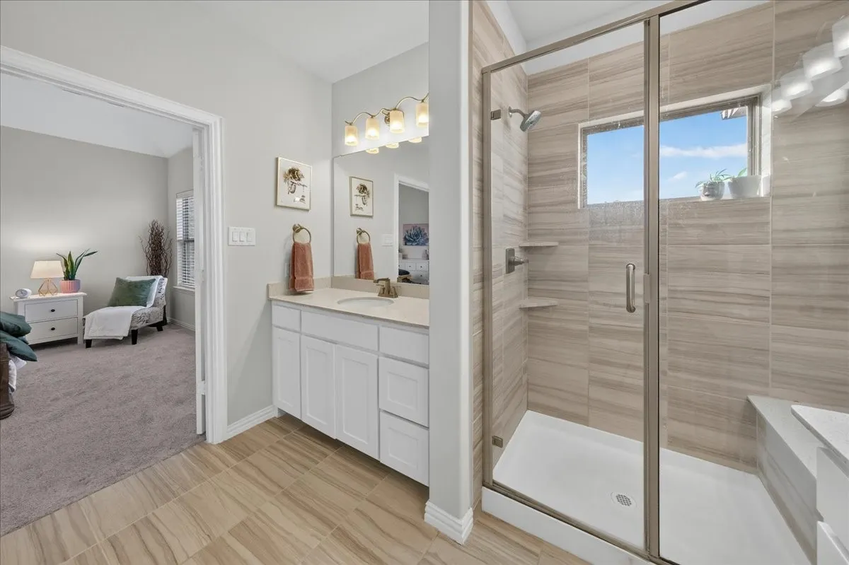Contemporary bathroom featuring a spacious shower enclosure with glass doors, stone-look tile walls, and a built-in bench