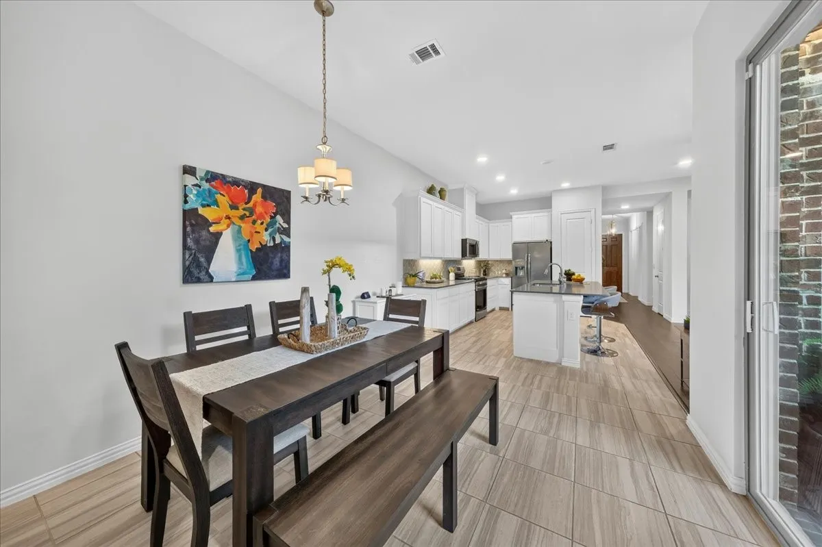 Open-concept dining area featuring a contemporary chandelier and wood-look tile flooring