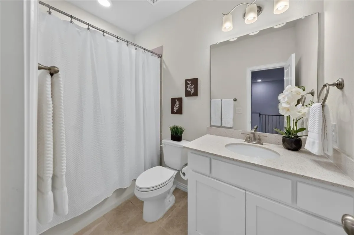 Bathroom featuring a white vanity with an integrated sink, a light-toned countertop, and brushed nickel fixtures