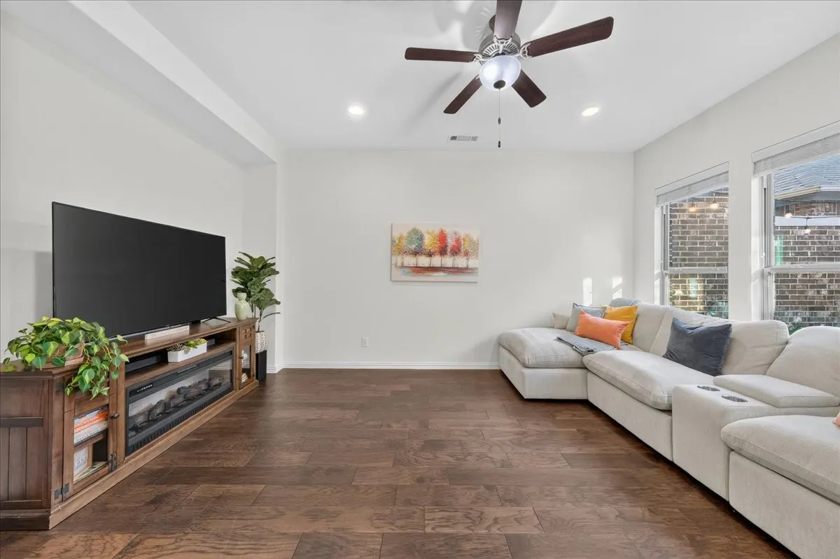 Spacious living area featuring wood-finish flooring, recessed lighting, and a ceiling fan with integrated light