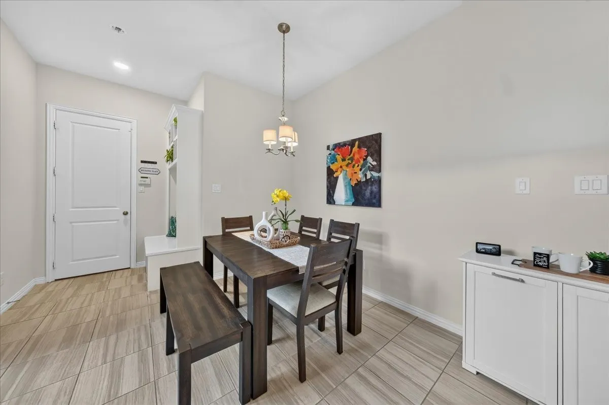 Dining area featuring a contemporary chandelier, vaulted ceilings, and large format tile flooring