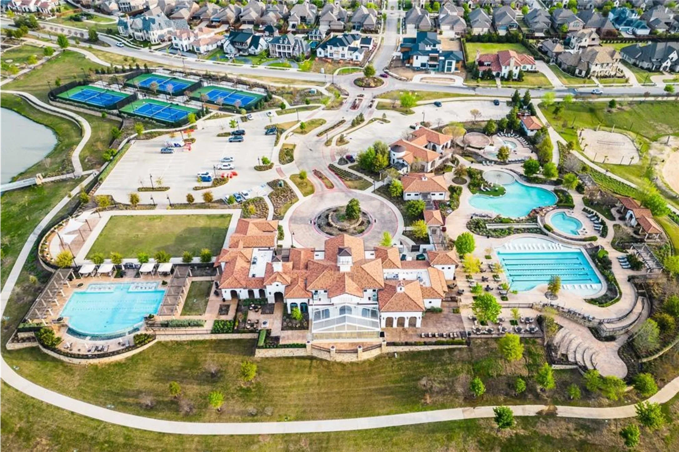 Expansive recreation center featuring multiple swimming pools, sports courts, and a central clubhouse with a red tile roof