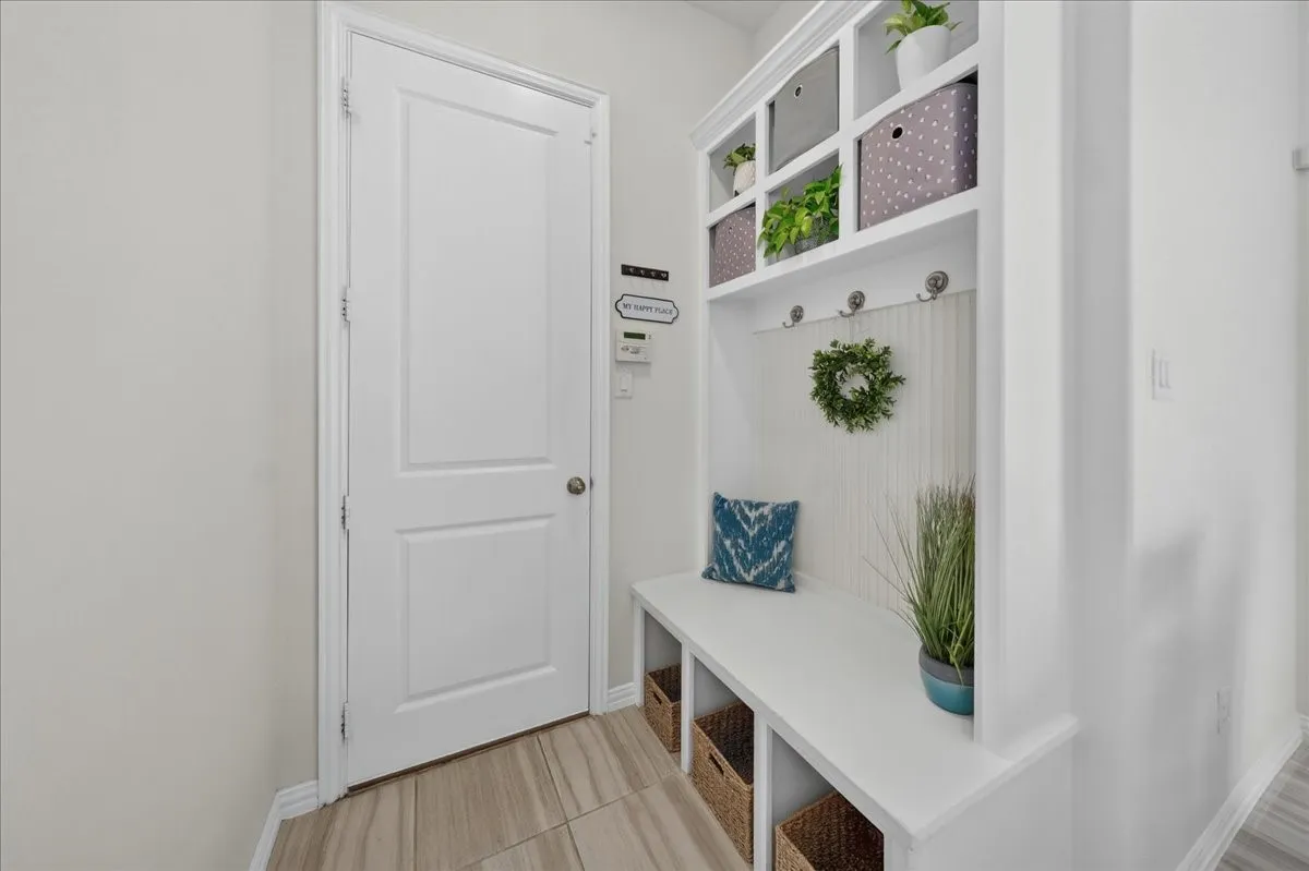 Built-in mudroom bench with cubby storage, upper shelving, beadboard backing, and coat hooks