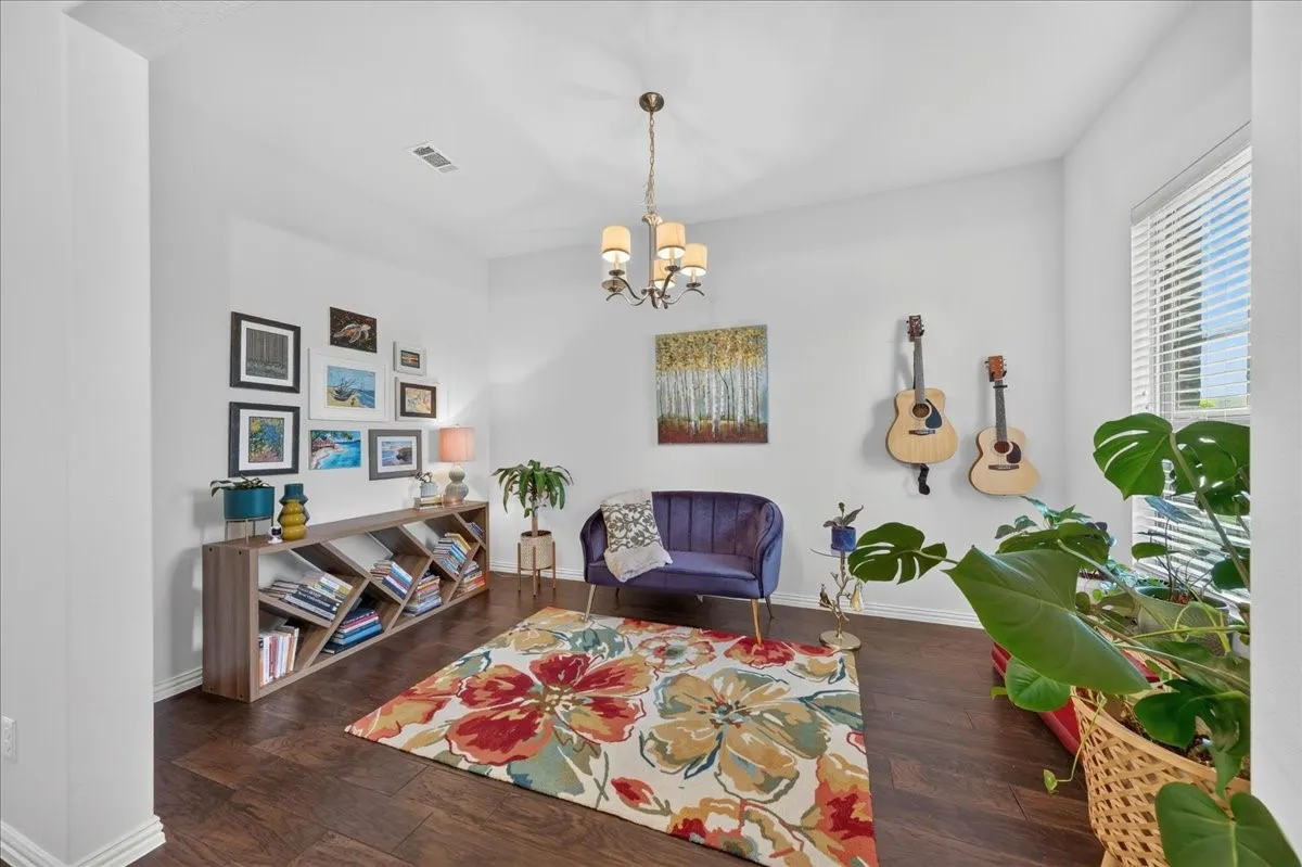 Spacious interior room featuring dark wood-finish flooring and ample natural light from a window with blinds