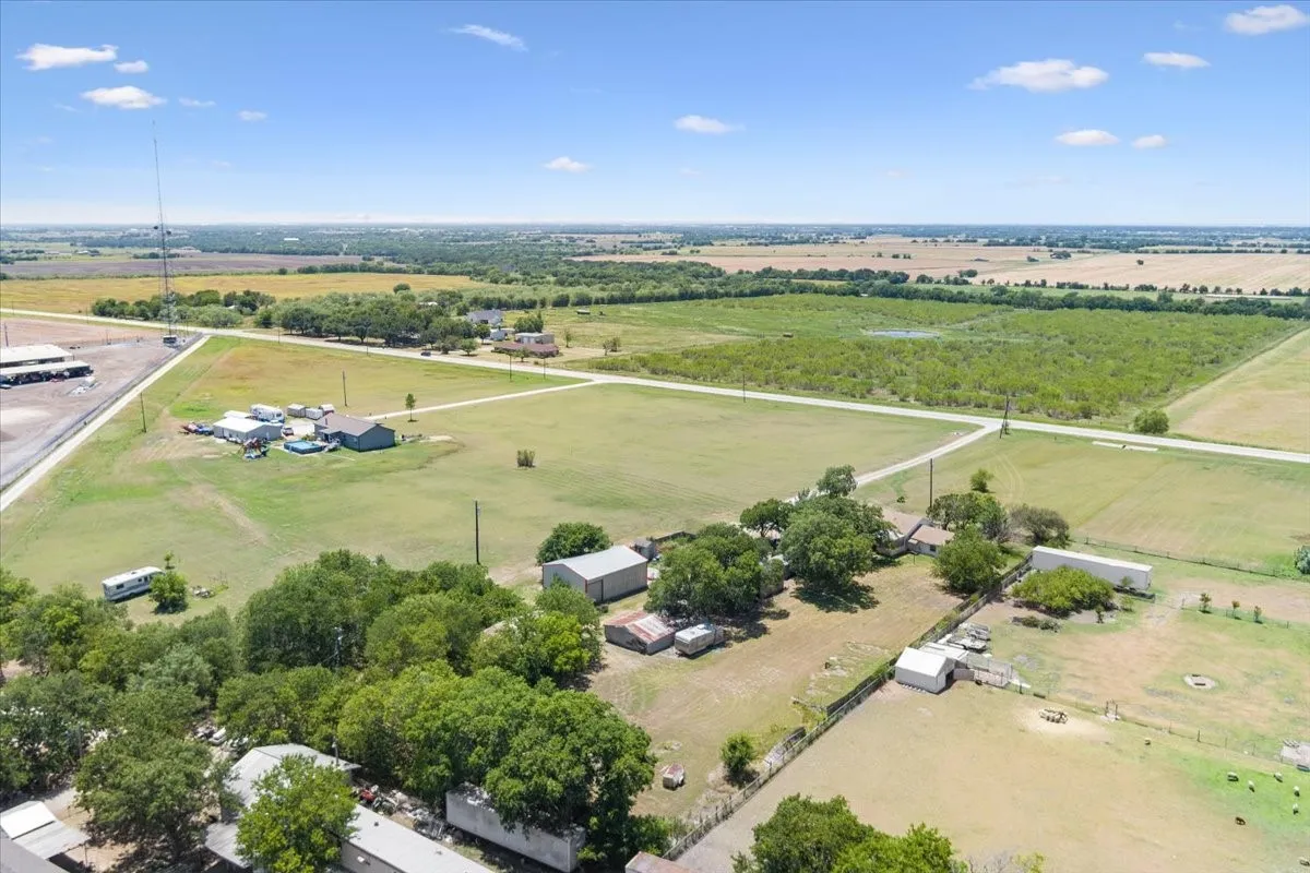 Expansive rural property featuring multiple structures, open fields, and distant agricultural land