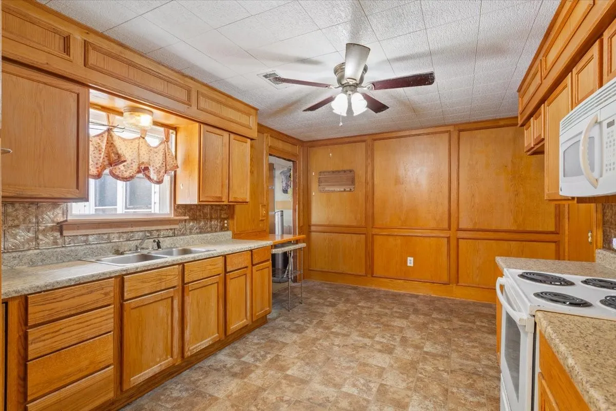 Kitchen featuring wood cabinetry, stone-look countertops, and a double basin sink