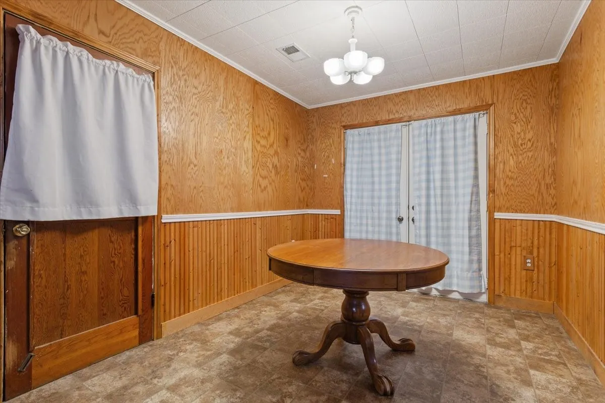Room with wood-panel walls, beadboard wainscoting, and tile-finish flooring