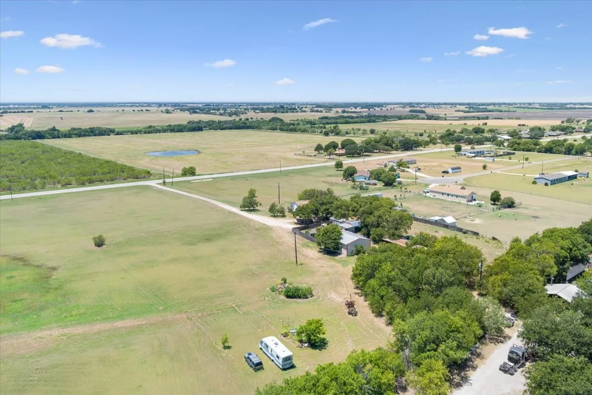 Expansive rural landscape featuring a pond, scattered residential structures, and extensive open fields