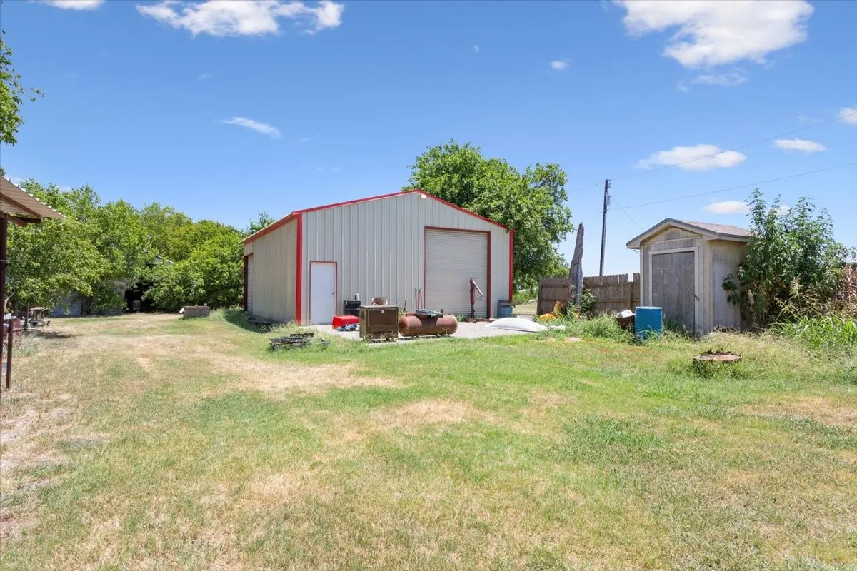 Spacious property featuring a large metal workshop building with a roll-up door and a separate side entry door