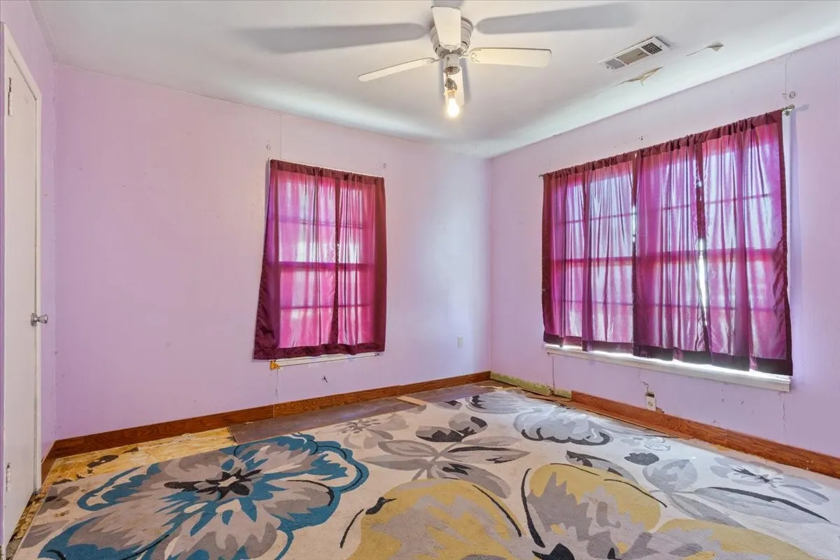 Room featuring a ceiling fan, two windows, and an interior door