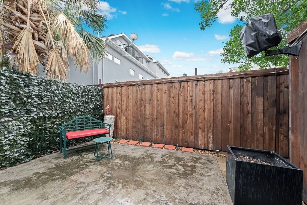 Private patio space featuring a concrete slab surface, wood fencing, and a vertical garden wall