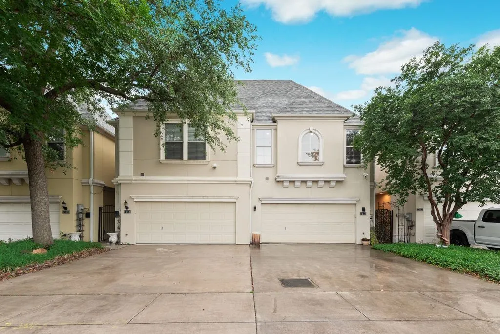 Stucco exterior featuring a dual garage and arched window details