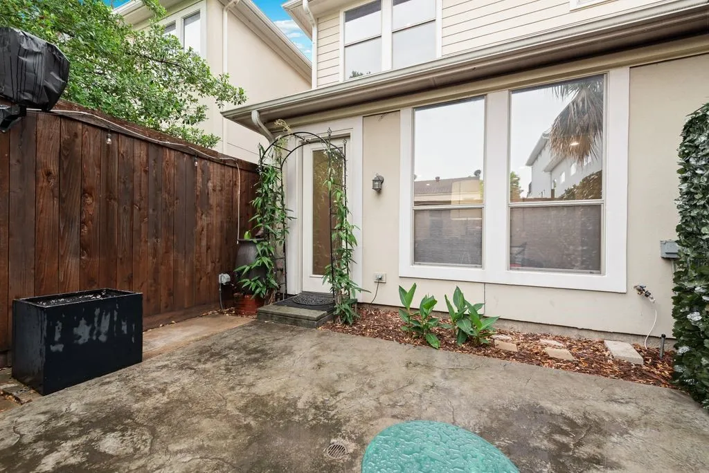 Private patio space featuring a concrete slab surface, wood privacy fence, and a decorative arched trellis at the entry