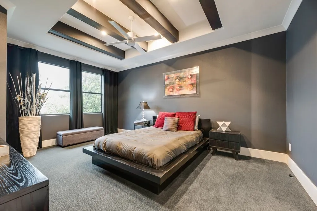 Spacious room featuring a tray ceiling with dark wood-finish beams, recessed lighting, and a ceiling fan