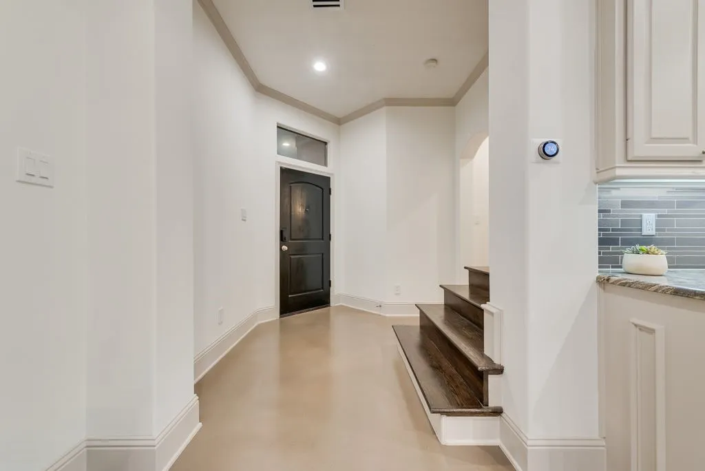 Entryway featuring a dark wood-finish door with transom window, light-toned flooring, and crown molding