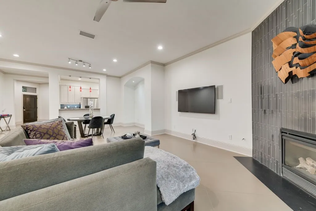 Open-concept living area featuring a tile fireplace with a sleek black surround, recessed lighting, and crown molding