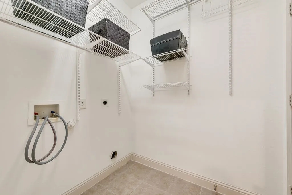 Dedicated laundry area featuring tile flooring, white baseboards, and white walls