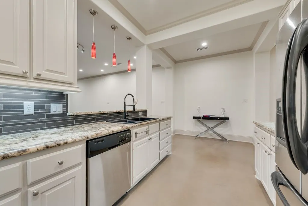Kitchen featuring light cabinetry, a stainless steel dishwasher, a black undermount sink with a matte black faucet, granite countertops, and a gray mosaic tile backsplash