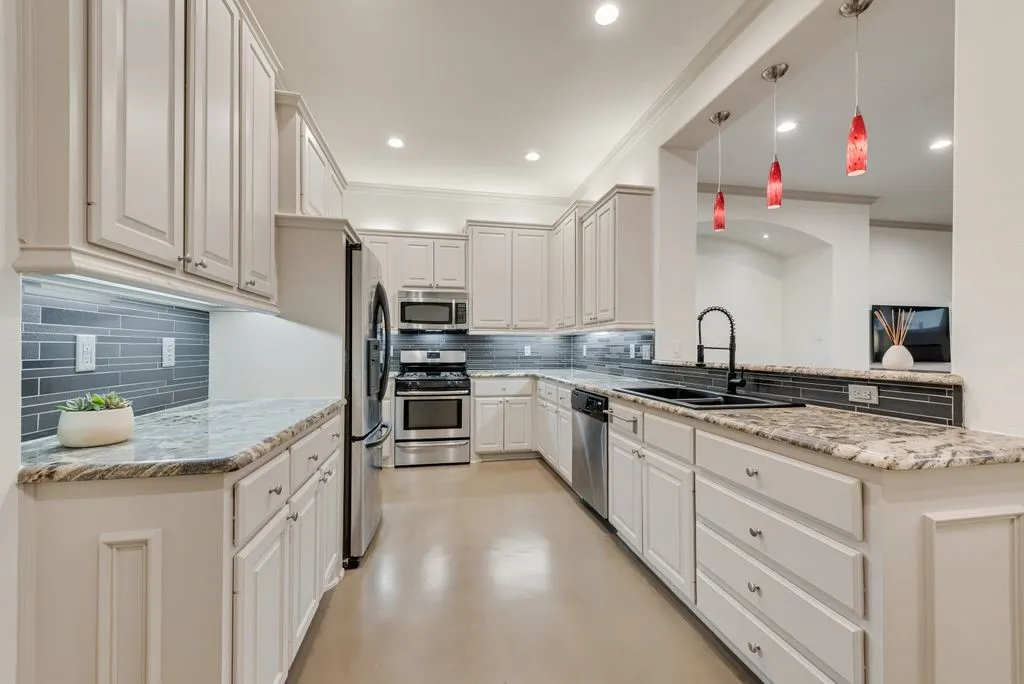 Elegant kitchen featuring crisp white cabinetry with recessed panel doors, granite countertops, and stainless steel appliances including a double-wall oven configuration