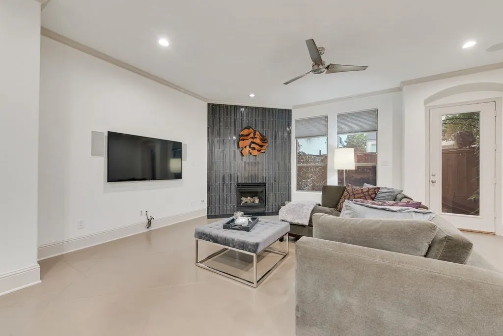 Living area with a contemporary tiled fireplace, integrated television, and a ceiling fan