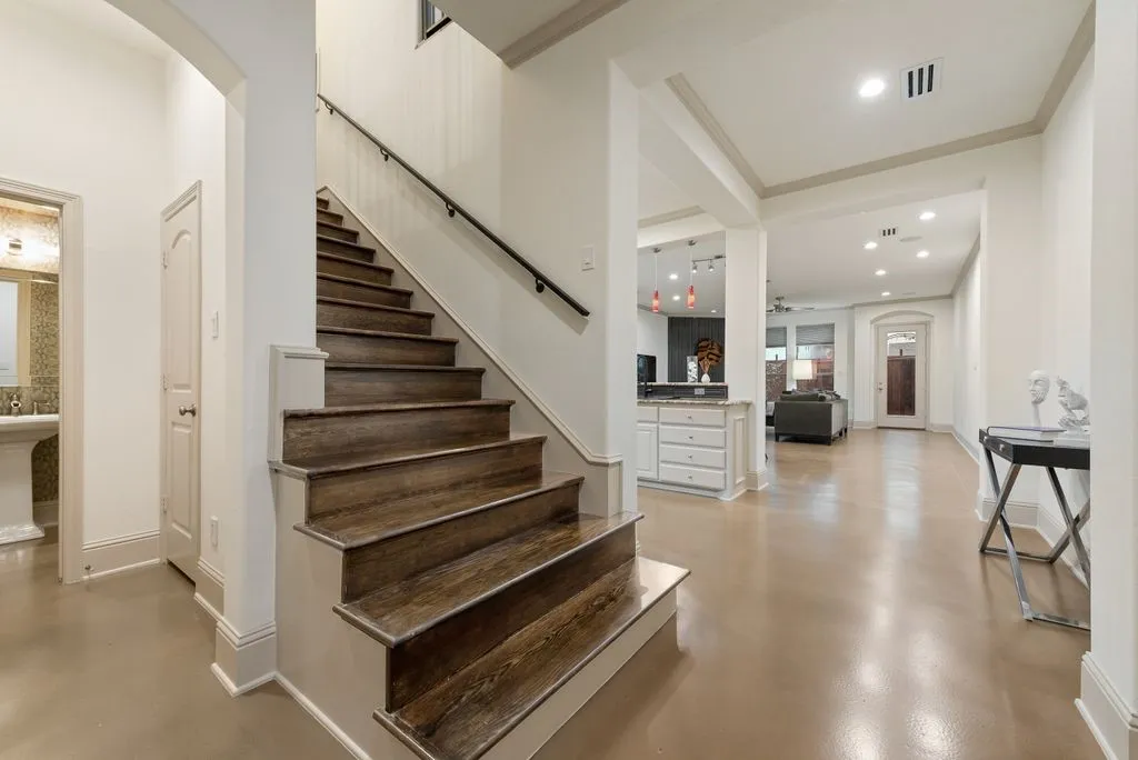 Wood-finish staircase with white risers and a dark handrail