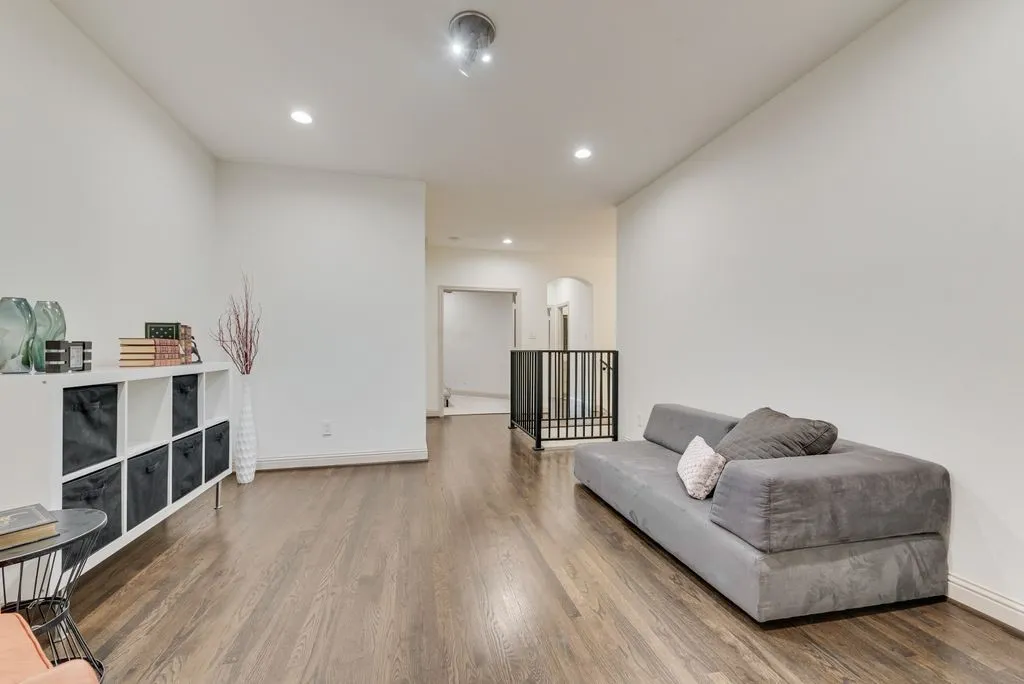 Spacious area featuring wood-finish flooring, recessed lighting, and a contemporary metal railing