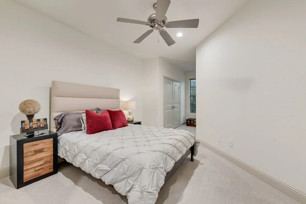 Carpeted bedroom featuring an upholstered headboard, a ceiling fan with integrated lighting, and white walls