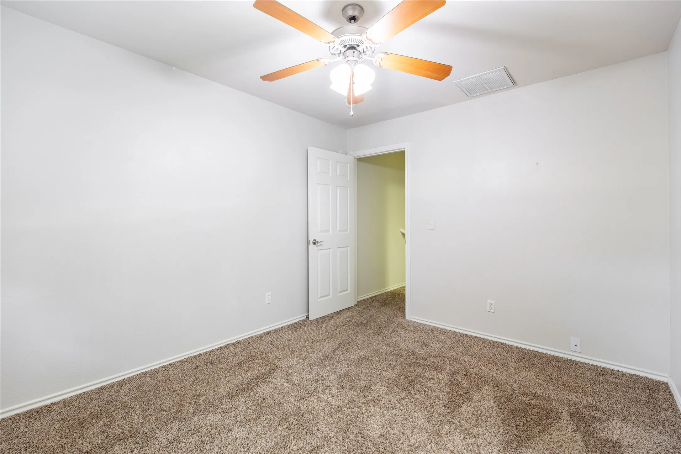 Carpeted room featuring a ceiling fan with integrated lighting, white walls, and white baseboards