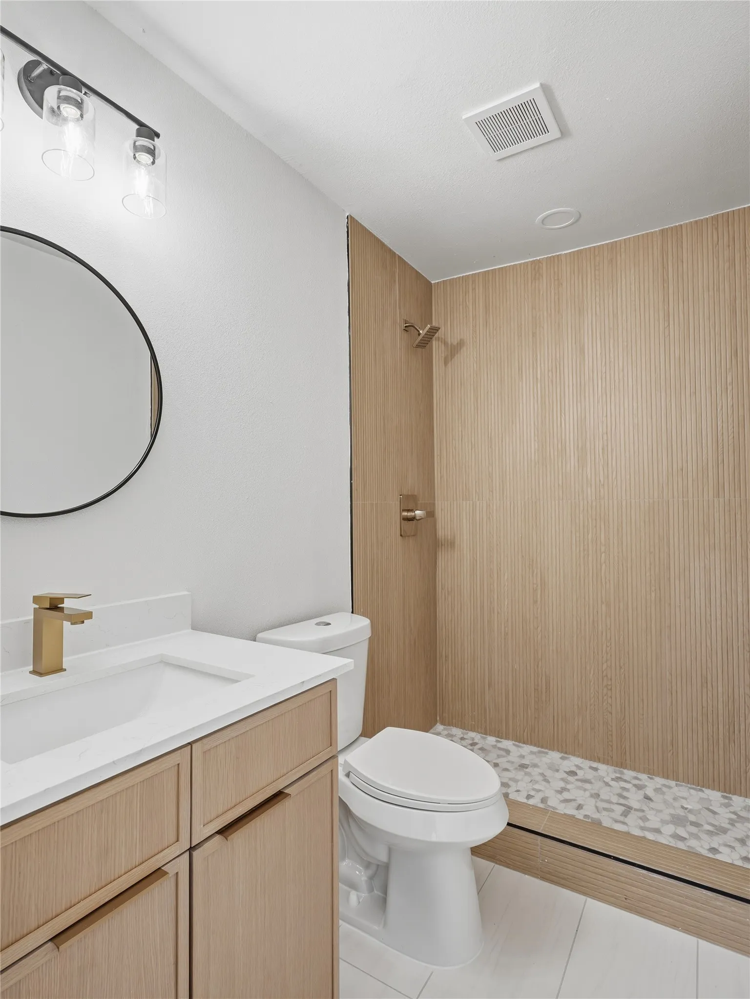 Modern bathroom featuring a wood-finish vanity with a white countertop and gold-finish faucet