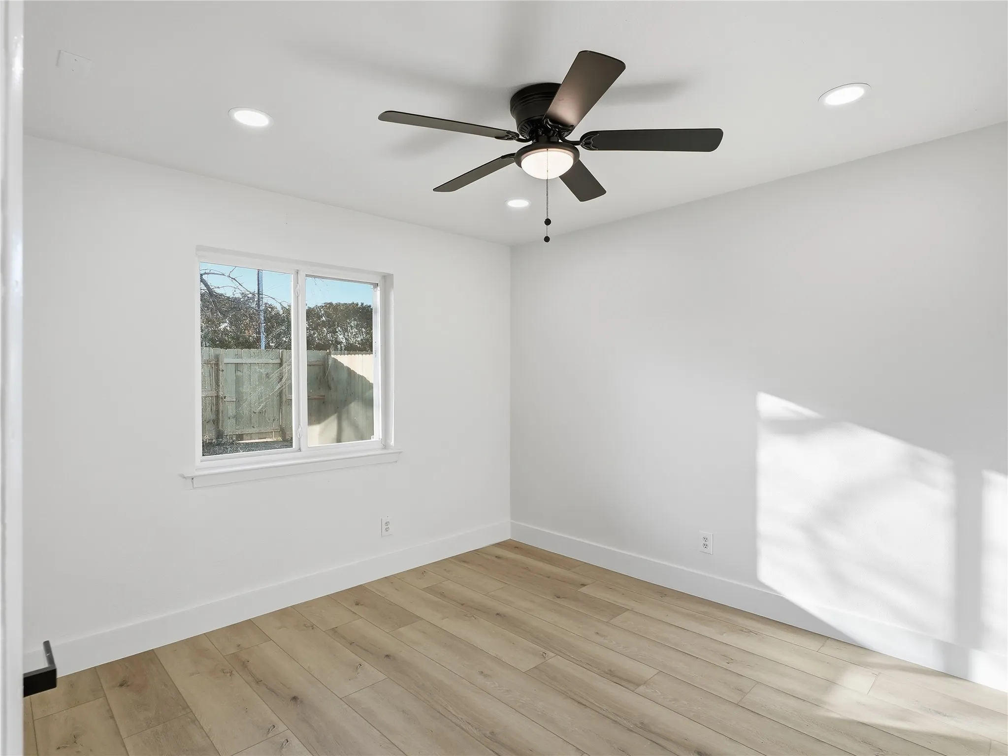 Bright interior space featuring a ceiling fan with integrated lighting, recessed lighting, and wood-finish flooring