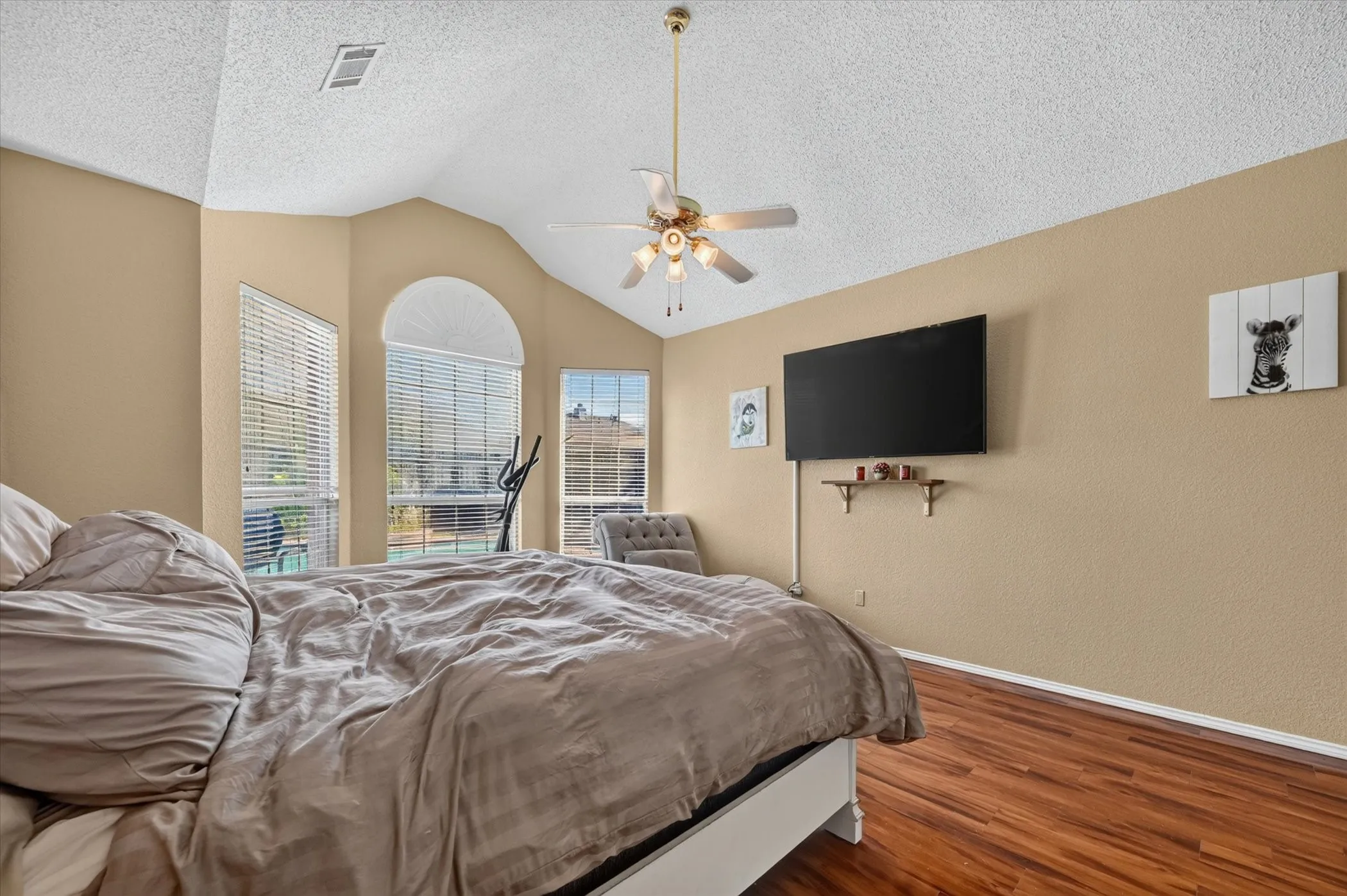 Vaulted ceiling interior featuring multiple windows with blinds, a ceiling fan, and wood-finish flooring
