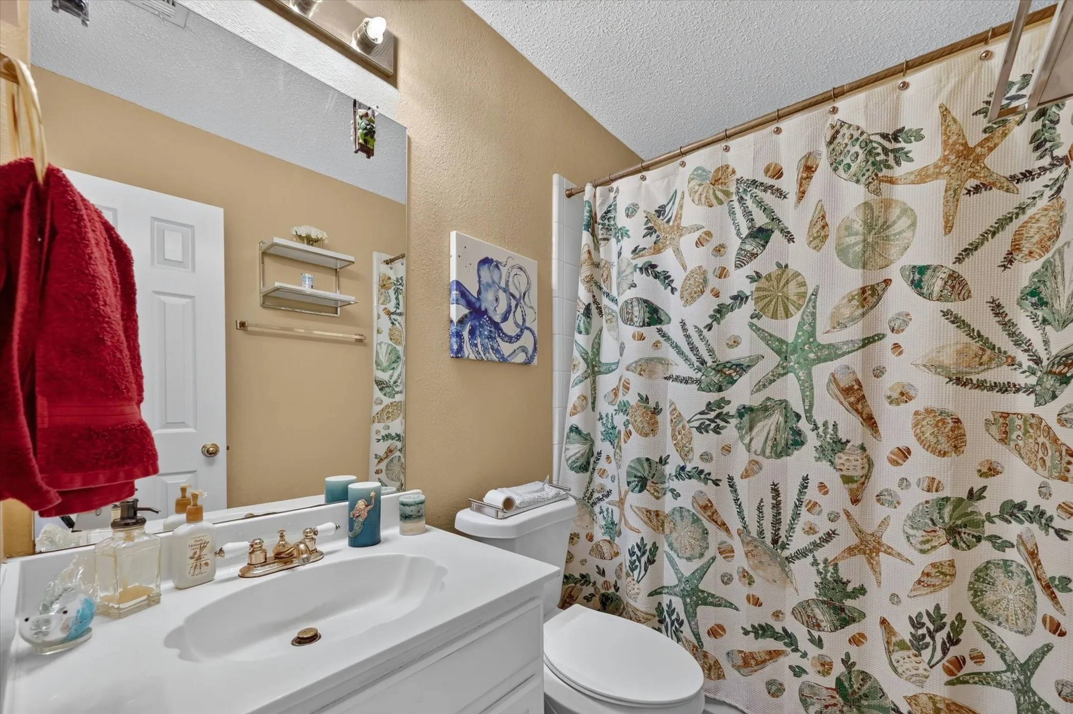Full bathroom featuring a white vanity with an integrated sink, a large wall-mounted mirror, a two-bulb vanity light fixture, and a toilet