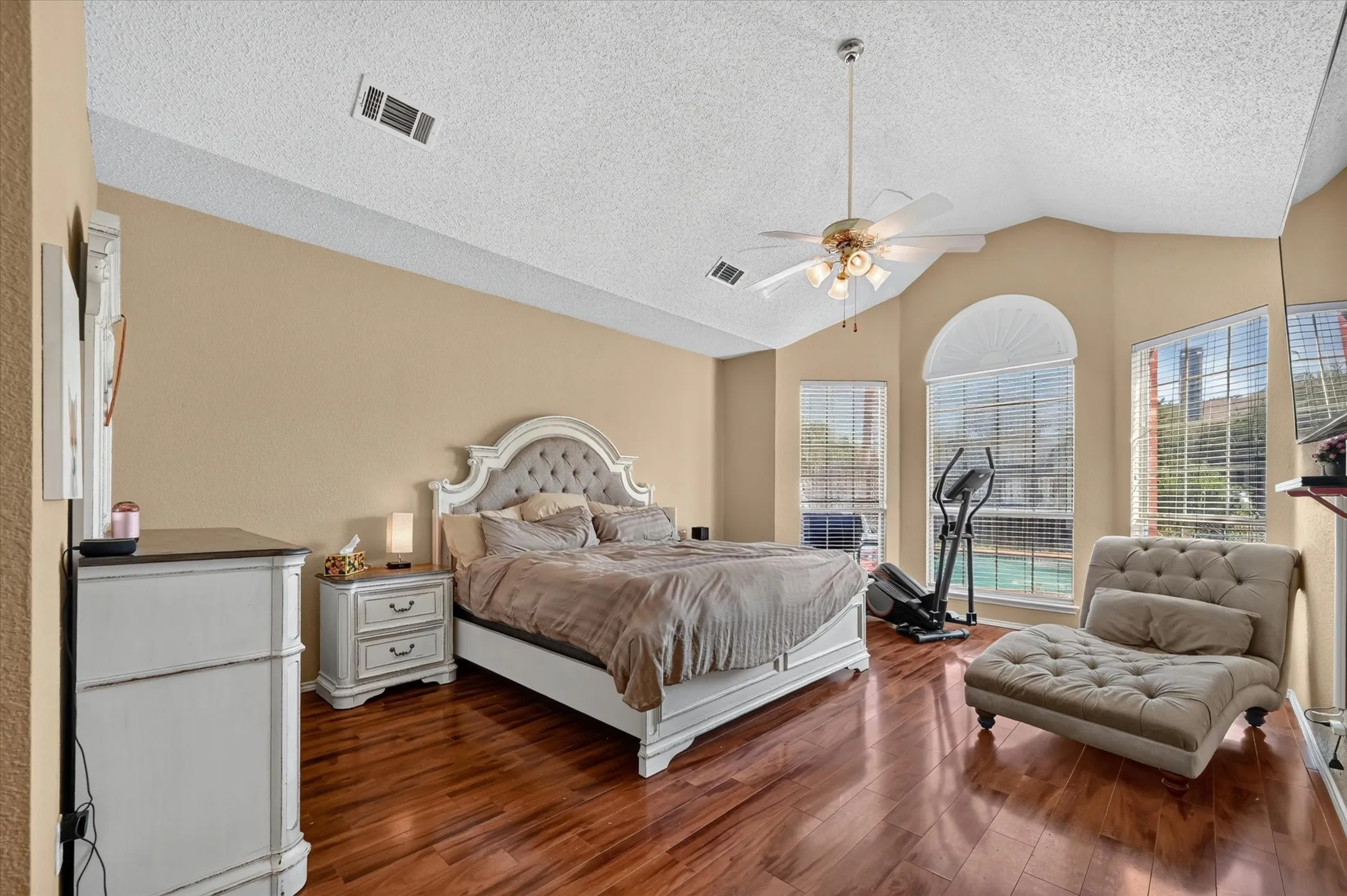 Vaulted ceiling bedroom featuring wood-finish flooring