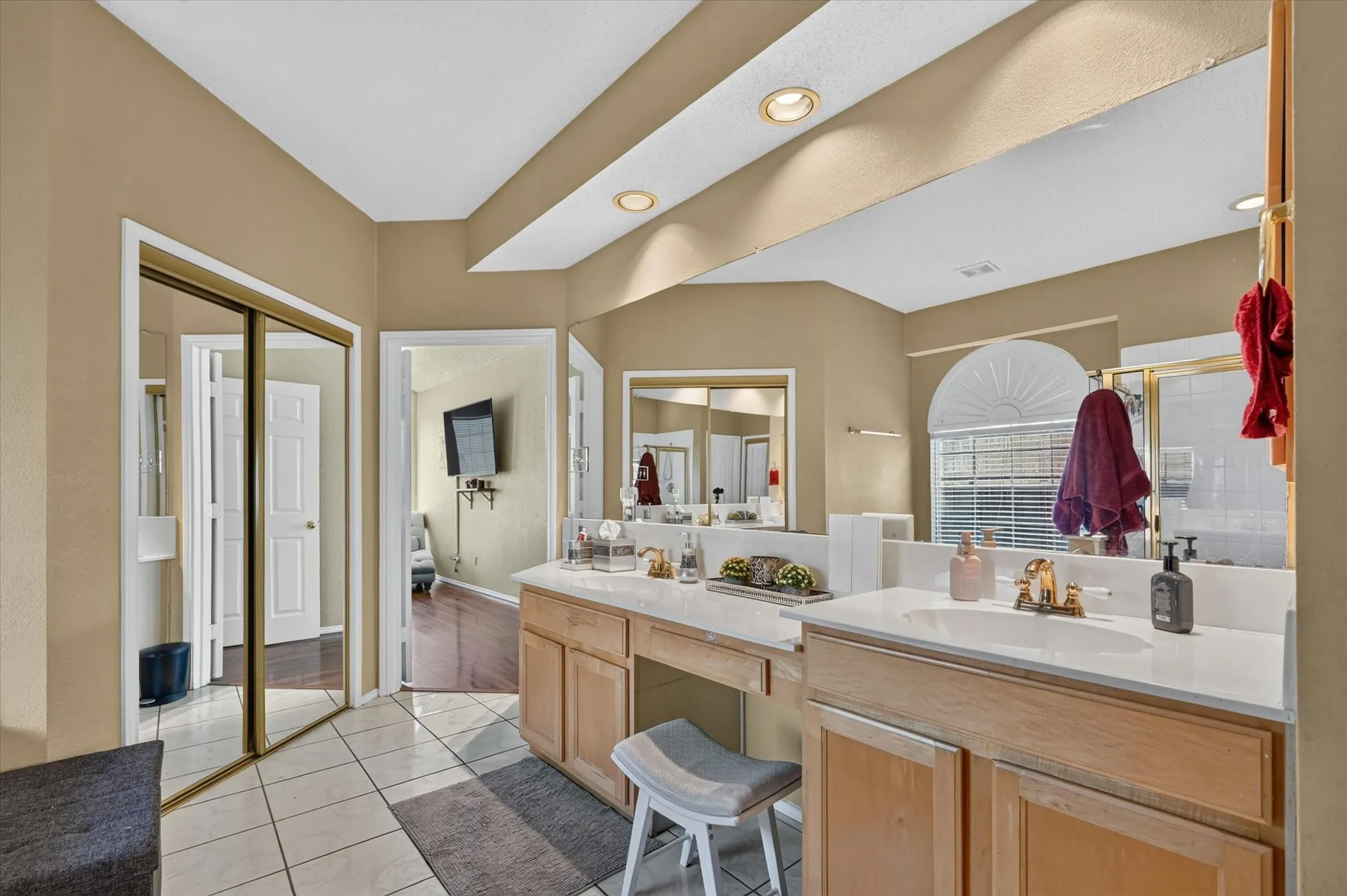 Bathroom featuring a dual vanity with light wood cabinetry, white countertops, and a full-width mirror
