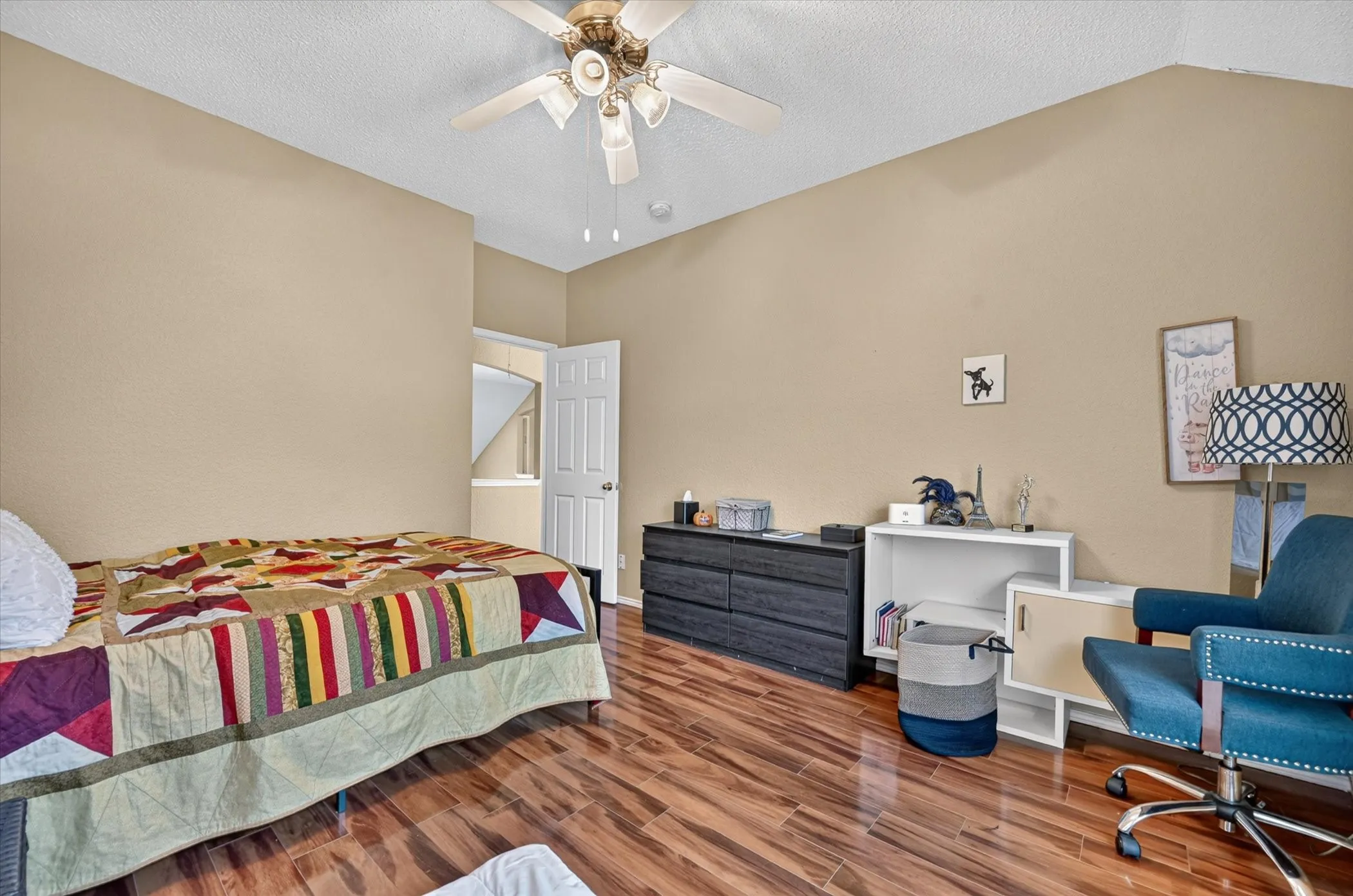Spacious bedroom featuring wood-finish flooring, soft neutral wall tones, and abundant natural light from recessed ceiling fixtures