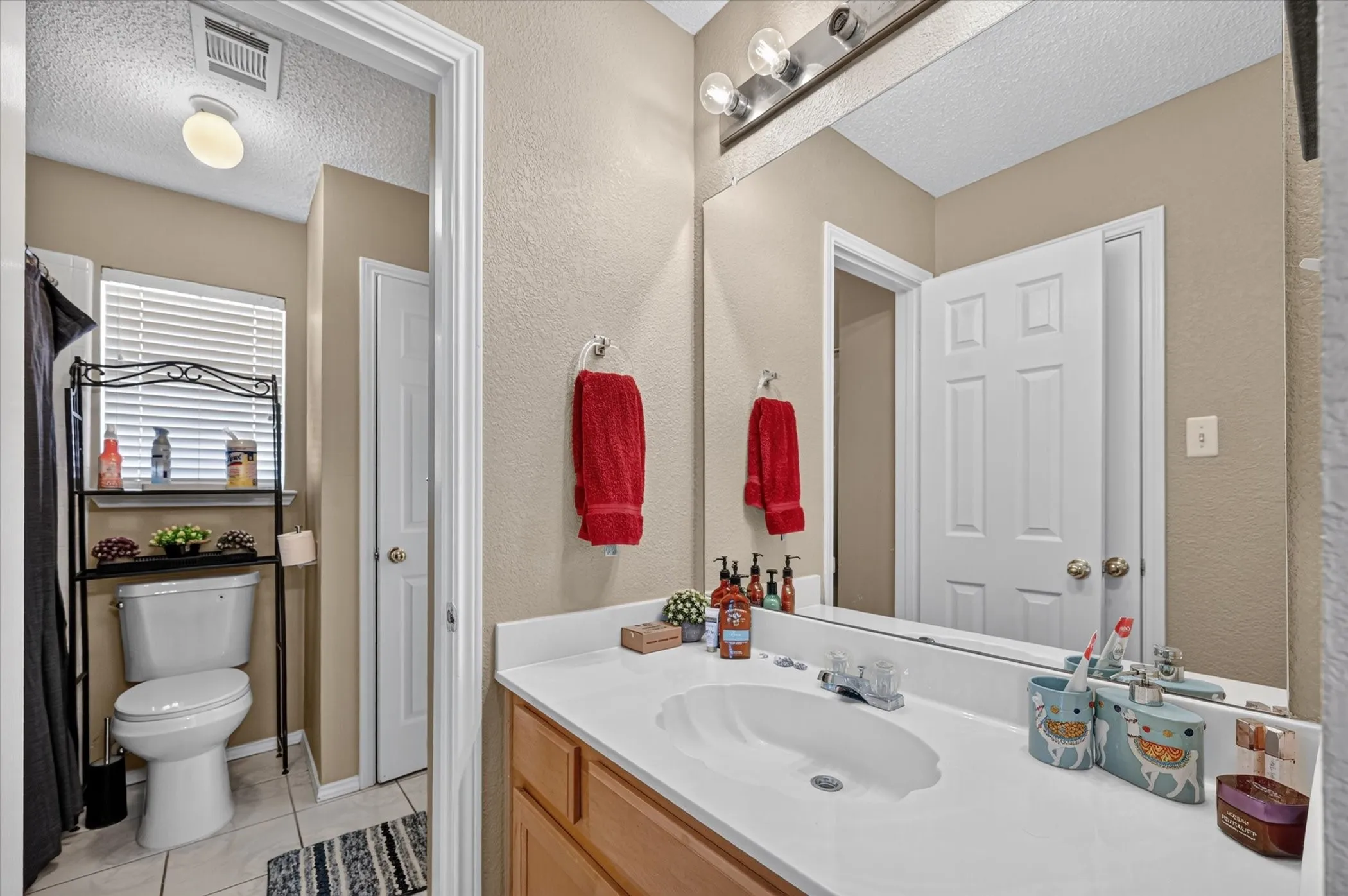 Full vanity mirror with sconce lighting, single basin sink, and wood-finish cabinetry