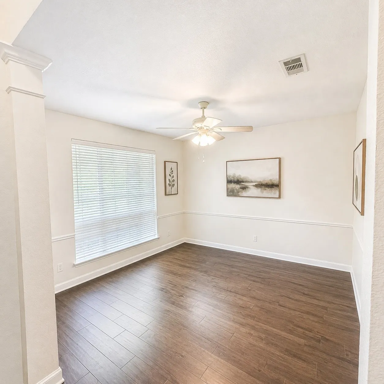 Spacious room featuring wood-finish flooring, a contemporary ceiling fan, and a large window with horizontal blinds